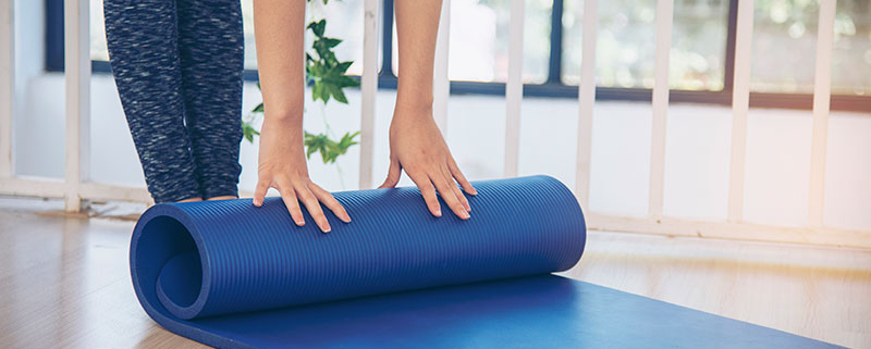 Person unrolling a blue yoga mat