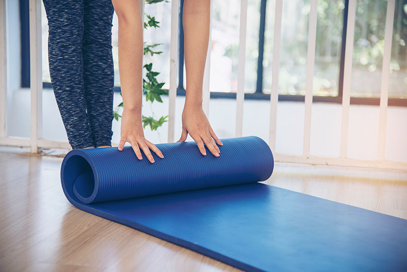 Person unrolling a blue yoga mat